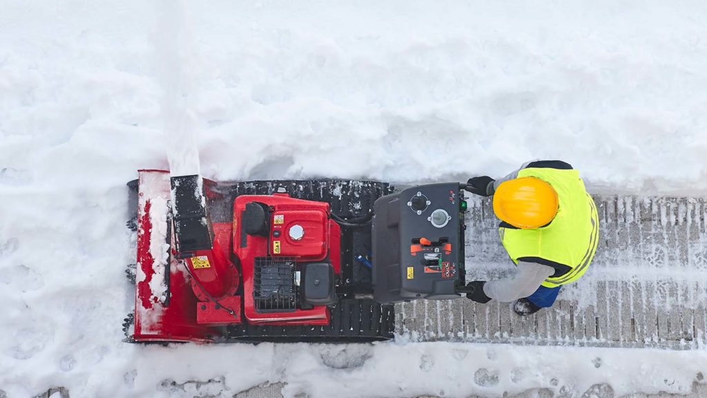 worker cleaning snow on the sidewalk